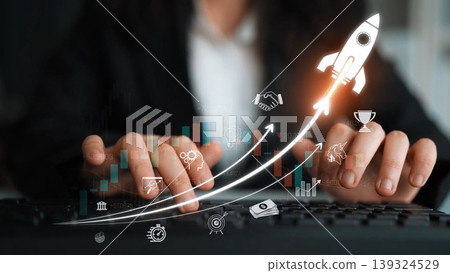 A business professional types on a keyboard while a rocket launch graphic symbolizes growth and success, showcasing a modern workspace filled with innovation and forward-thinking ideas. Sigmoid A business professional types on a keyboard while a rocket launch graphic symbolizes growth and success, showcasing a modern workspace filled with innovation and forward-thinking ideas. Sigmoid 139324529