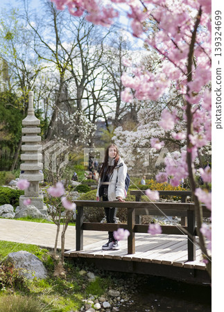 Woman enjoying cherry blossoms in a tranquil Japanese garden. Early nature awakening. 139324699