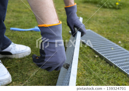 Maintenance task of a metal outdoor drain grate, focusing on proper safety gear and careful handling. 139324701
