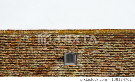 Old tiled roof with arched dormer windows, suitable for design and background use. 139324702