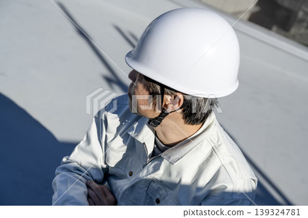 一名男工人在檢查一棟獨立房屋的平屋頂。 一名男工人在檢查一棟獨立房屋的平屋頂。 139324781