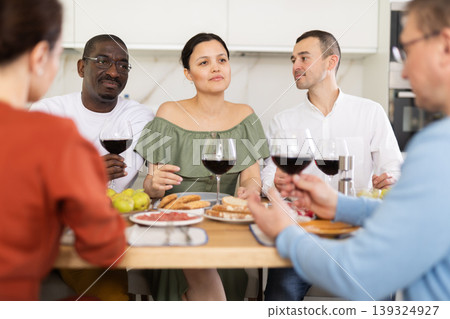 Happy adult friends at the festive table discussing news and drinking red wine Happy adult friends at the festive table discussing news and drinking red wine 139324927