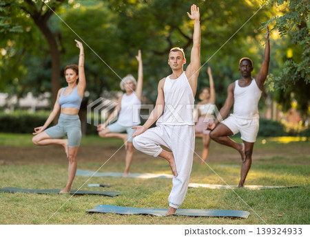 Group of multinational people practitioner performing Garudasana in garden 139324933