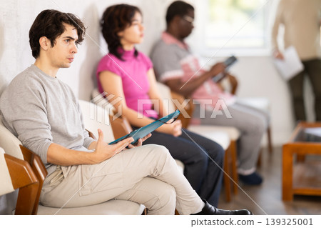 Young guy sitting in a queue at a modern office Young guy sitting in a queue at a modern office 139325001