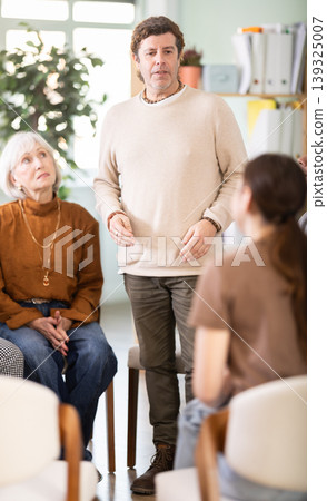 Middle-aged man standing and speaking during circle discussion Middle-aged man standing and speaking during circle discussion 139325007