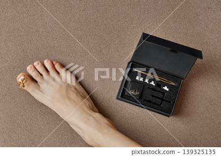 Nail corrector kit displayed with foot on textured surface in indoor setting 139325135