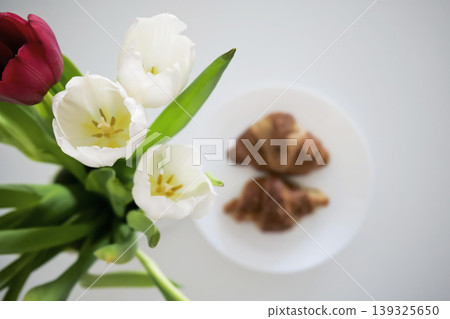 White and red tulips in a vase and croissants on a plate in the background  139325650