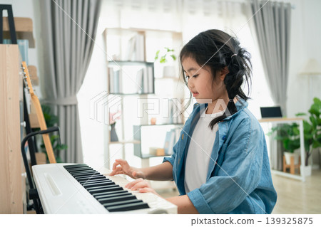 Young girl playing piano at home with focus on musical education, creativity, and childhood development in bright and airy living room setting Young girl playing piano at home with focus on musical education, creativity, and childhood development in bright and airy living room setting 139325875