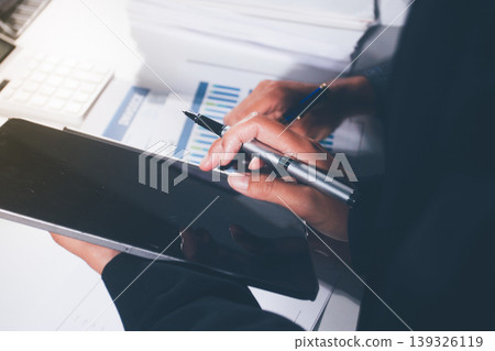 Professional photo of a person's hands reviewing a contract or legal document on a desk, for concepts of business, finance, and legal affairs 139326119