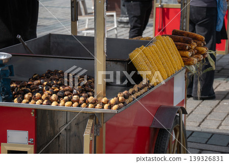 Street food cart with roasted chestnuts and grilled corn in Istanbul outdoor market with metal tray, cooking setup. Street food, local cuisine, tourism marketing, urban food culture, travel content Street food cart with roasted chestnuts and grilled corn in Istanbul outdoor market with metal tray, cooking setup. Street food, local cuisine, tourism marketing, urban food culture, travel content 139326831