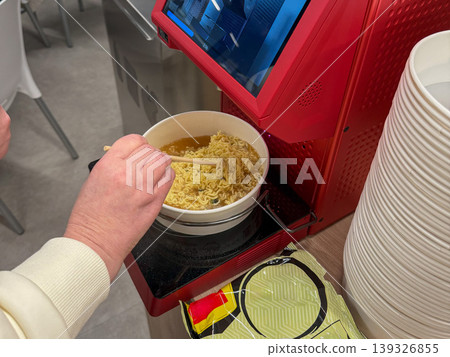 Instant noodle preparation in automatic ramen machine with bowl, chopsticks, control panel in food service setting. Convenience food, self service, quick meal, catering equipment, dining concept Instant noodle preparation in automatic ramen machine with bowl, chopsticks, control panel in food service setting. Convenience food, self service, quick meal, catering equipment, dining concept 139326855