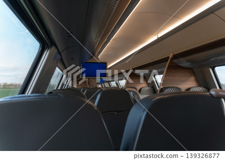 Train interior with empty seats, window view and onboard screen in Belgium under soft lighting. Transportation concept, travel content, mobility service, passenger experience, business Train interior with empty seats, window view and onboard screen in Belgium under soft lighting. Transportation concept, travel content, mobility service, passenger experience, business 139326877