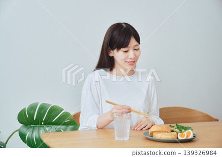 一位女士正在吃早餐；一個自然、日常的用餐場景。 139326984