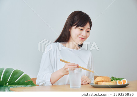 A woman eating breakfast; a natural, everyday meal scene. A woman eating breakfast; a natural, everyday meal scene. 139326986