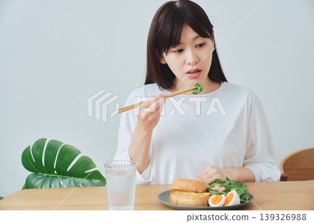 A woman eating breakfast; a natural, everyday meal scene. A woman eating breakfast; a natural, everyday meal scene. 139326988