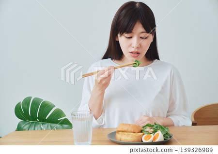 一位女士正在吃早餐;一個自然、日常的用餐場景。 一位女士正在吃早餐;一個自然、日常的用餐場景。 139326989
