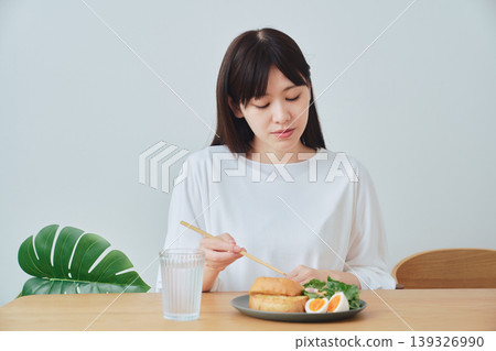 一位女士正在吃早餐;一個自然、日常的用餐場景。 一位女士正在吃早餐;一個自然、日常的用餐場景。 139326990