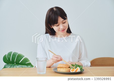 A woman eating breakfast; a natural, everyday meal scene. A woman eating breakfast; a natural, everyday meal scene. 139326991
