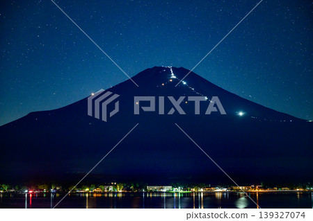 在暮色中,富士山上登山者們擺出的人體造型在燈光的襯托下熠熠生輝。 在暮色中,富士山上登山者們擺出的人體造型在燈光的襯托下熠熠生輝。 139327074