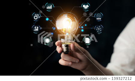 Bright Idea Symbolizing Innovation and Technology with Hand Holding Light Bulb Surrounded by Digital Icons Representing Business Growth and Connectivity Quark 139327212