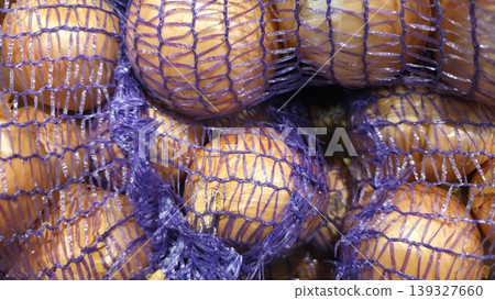 Fresh golden onions packed in a purple mesh bag at a grocery store Fresh golden onions packed in a purple mesh bag at a grocery store 139327660