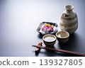 一幅傳統的日本圖片，描繪了熱清酒、醃菜、清酒壺和清酒杯。 139327805