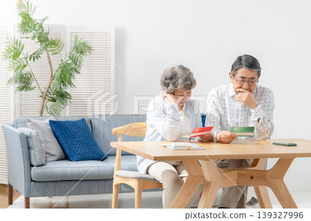 A senior couple reflects while looking at their bankbook. A senior couple reflects while looking at their bankbook. 139327996