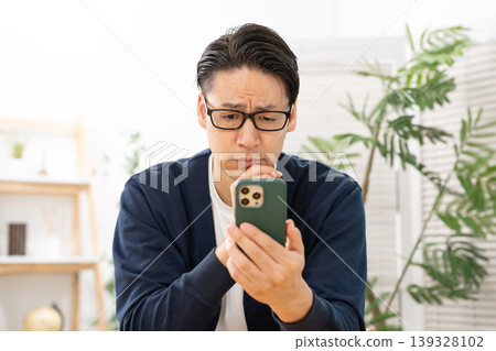 A man who is worried about seeing a smartphone A man who is worried about seeing a smartphone 139328102