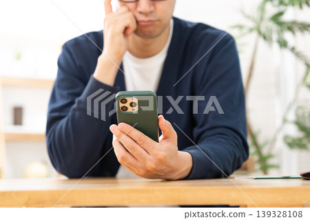 A man looking at his smartphone and pondering 139328108