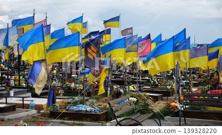 View on countless graves of ukrainian soldiers alley of glory in Kharkiv decorated with waving blue-yellow flags. The site commemorates soldiers who died during russian invasion in Ukraine. Slow mo View on countless graves of ukrainian soldiers alley of glory in Kharkiv decorated with waving blue-yellow flags. The site commemorates soldiers who died during russian invasion in Ukraine. Slow mo 139328220