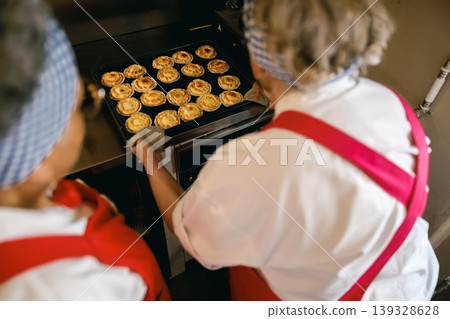Close up of senior women holding a tray of freshly baked tarts from the oven Close up of senior women holding a tray of freshly baked tarts from the oven 139328628