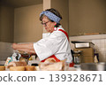 Middleaged baker joyfully combines ingredients in cozy kitchen setting 139328671