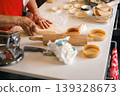 Close up of hands pressing dough on a floured table with baking tools nearby 139328673