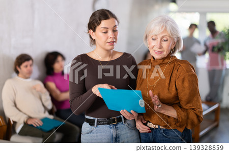 Young female secretary talking with mature woman in reception area Young female secretary talking with mature woman in reception area 139328859