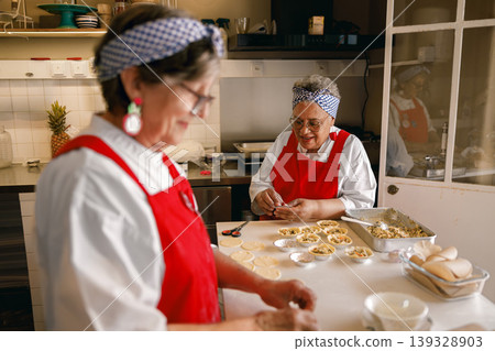Senior Caucasian and Black Women Chefs Preparing Pastries in Professional Kitchen Bakery Senior Caucasian and Black Women Chefs Preparing Pastries in Professional Kitchen Bakery 139328903