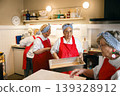 Senior Black and Caucasian women in red aprons working together in a community kitchen setting 139328912