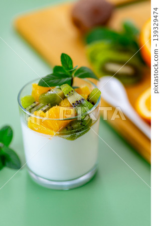 creamy yogurt dessert with kiwi and orange on green background creamy yogurt dessert with kiwi and orange on green background 139329474