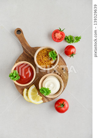 Top view of three small bowls with mayonnaise, ketchup, and mustard a light background Top view of three small bowls with mayonnaise, ketchup, and mustard a light background 139329639