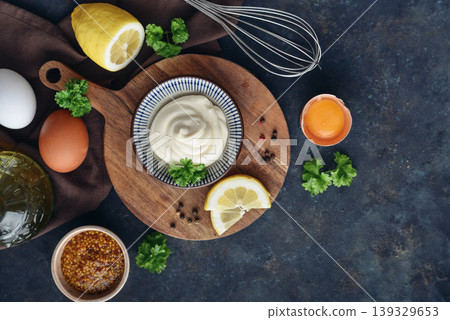 Top view of homemade mayonnaise in a bowl on a wooden board with fresh ingredients Top view of homemade mayonnaise in a bowl on a wooden board with fresh ingredients 139329653