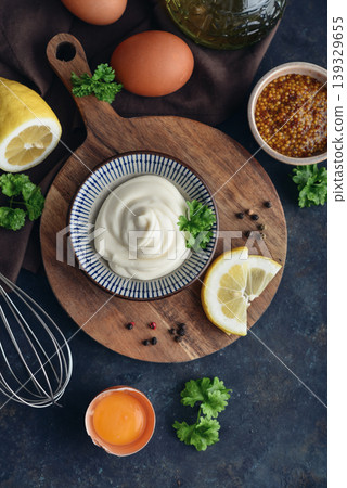 Top view of homemade mayonnaise in a bowl on a wooden board with fresh ingredients Top view of homemade mayonnaise in a bowl on a wooden board with fresh ingredients 139329655