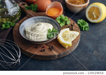 Homemade mayonnaise in a bowl on a wooden board with fresh ingredients 139329658