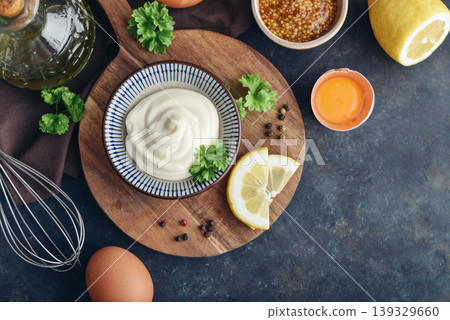Top view of homemade mayonnaise in a bowl on a wooden board with fresh ingredients Top view of homemade mayonnaise in a bowl on a wooden board with fresh ingredients 139329660