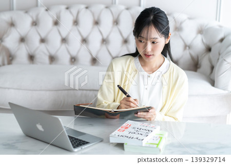 一位年輕女子正在上網課時做筆記。 一位年輕女子正在上網課時做筆記。 139329714