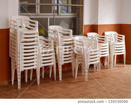 Stacked white plastic chairs preparing for public events Stacked white plastic chairs preparing for public events 139330090