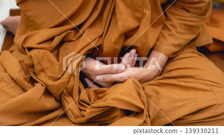 Close-up of Buddhist Monk in Saffron Robe Practicing Meditation and Mindfulness 139330211