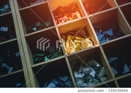 Colorful glass mosaic tiles in organized grid compartments for art and craft design, Assorted vibrant mosaic pieces collection for creative projects and decorative patterns 139330644
