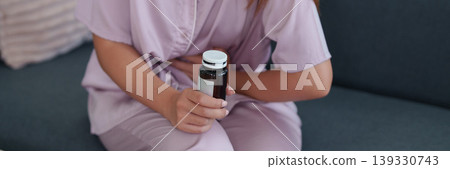 Asian women holding medicine bottle vitamin supplement pill container sitting on sofa at home for daily health wellness routine morning self care lifestyle Asian women holding medicine bottle vitamin supplement pill container sitting on sofa at home for daily health wellness routine morning self care lifestyle 139330743