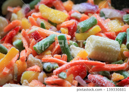 Assorted sliced frozen vegetables with ice crystals including colorful peppers carrots and baby corn Assorted sliced frozen vegetables with ice crystals including colorful peppers carrots and baby corn 139330881