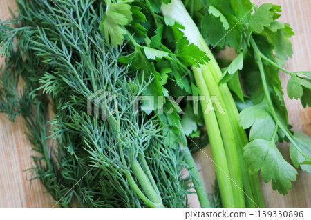 Fresh organic bunch of green dill parsley and celery on wooden board for healthy cooking nutrition Fresh organic bunch of green dill parsley and celery on wooden board for healthy cooking nutrition 139330896