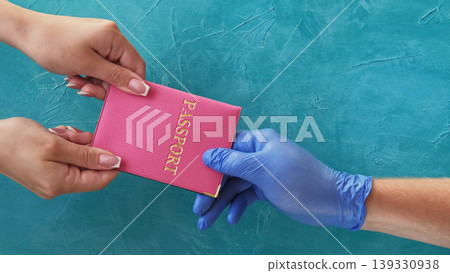 Passport control. Travel hygiene. Customs officer hand in protective glove taking female passenger id on blue copy space background. 139330938